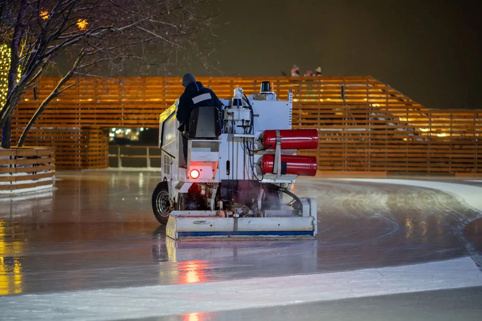 A machine is cleaning a ice rink at night.