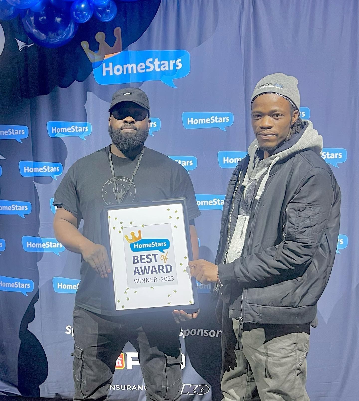 Two men pose at a HomeStars event holding a Best of Award plaque.