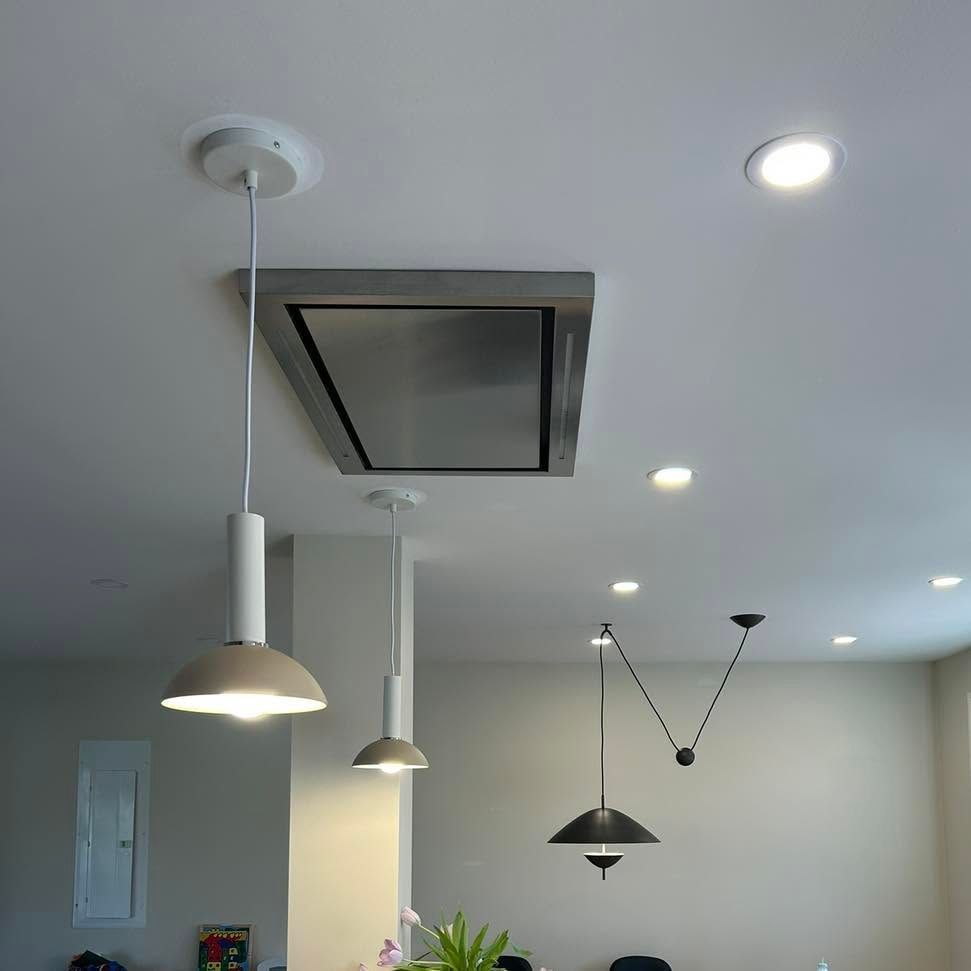 Person on a ladder installs a ceiling light fixture in a room