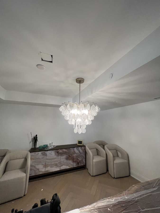 Elegant living room with crystal chandelier, beige sofas, and a decorative console table under a sloped ceiling