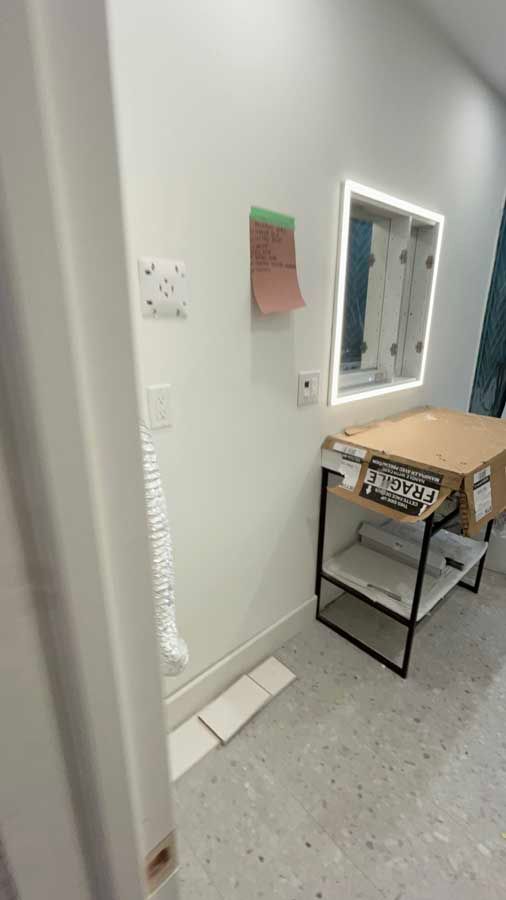 Small room with wall mirror, desk, chair, and wall notes on a gray floor.