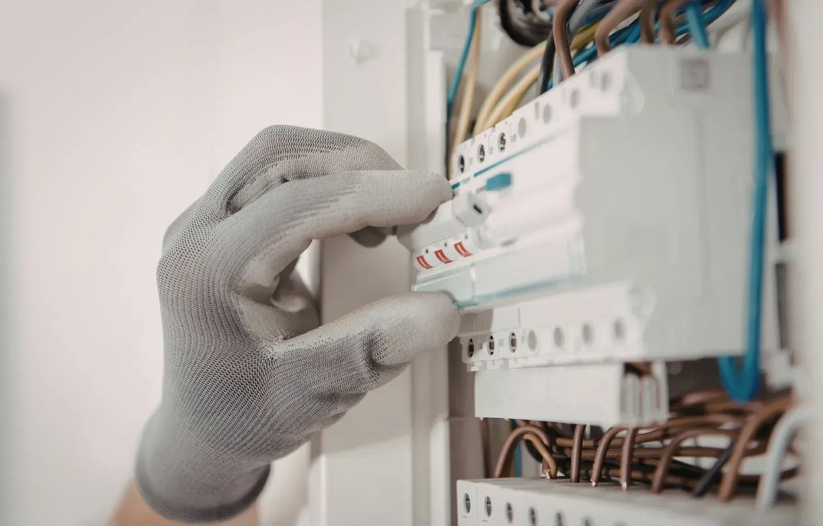 Two electricians in hard hats inspect open electrical panels in a construction site.