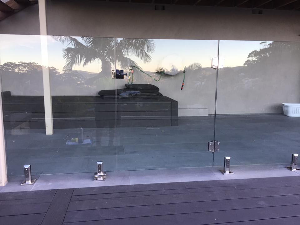 A Glass Fence Surrounds A Patio With A Couch In The Background — Avoca Beach Glass In Terrigal, NSW