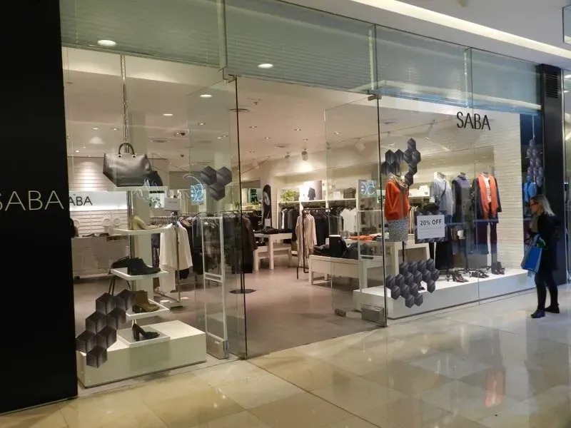 A Woman Is Standing In Front Of A Clothing Store In A Mall — Avoca Beach Glass In Green Point, NSW