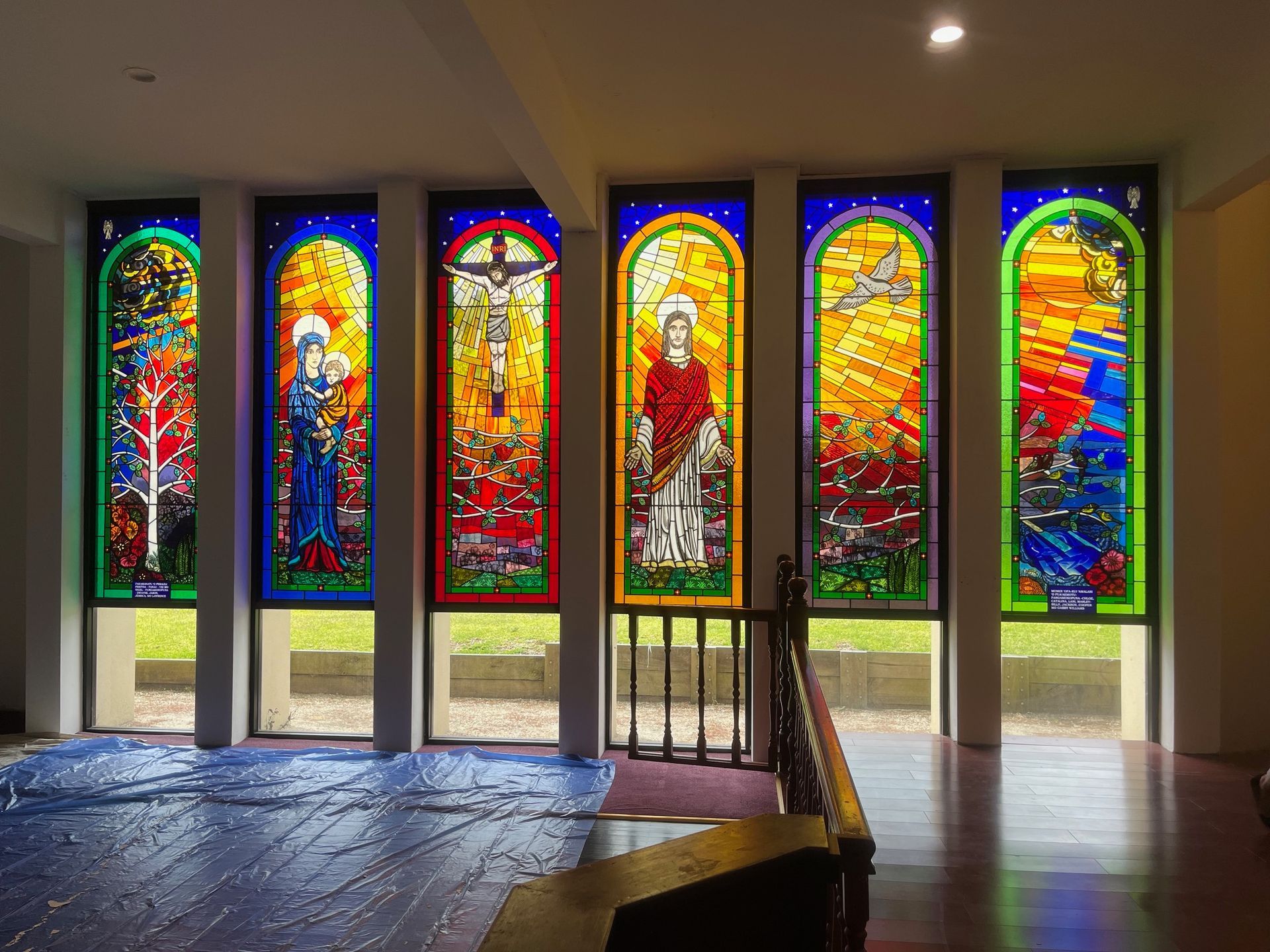 A Woman Is Standing In Front Of A Row Of Stained Glass Windows In A Church — Avoca Beach Glass In Erina, NSW