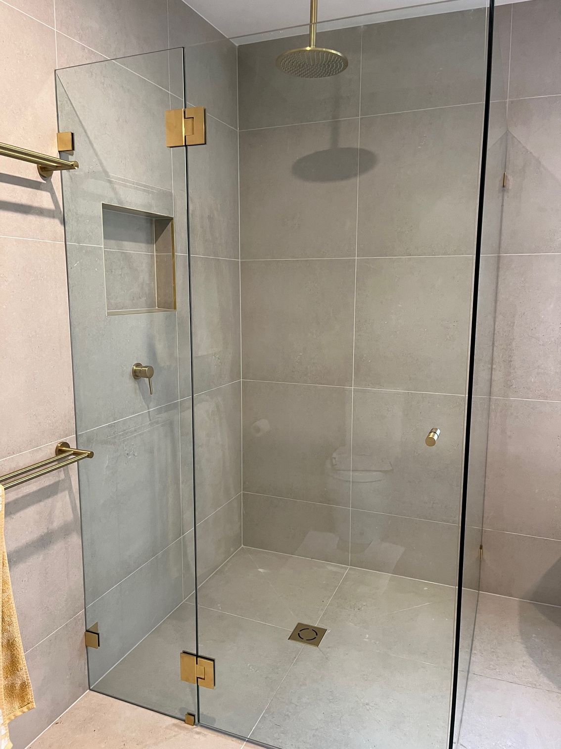 A bathroom with a walk in shower with a glass door and a shower head — Avoca Beach Glass In West Gosford, NSW