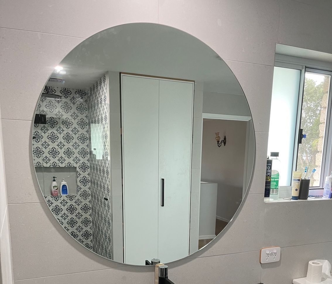 A bathroom with a round mirror and a sink — Avoca Beach Glass In West Gosford, NSW