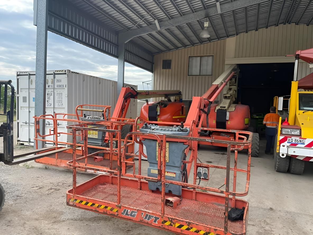 A Couple Of Orange Bucket Lifts Are Parked In Front Of A Building — Mackay Hose Fitting Services In West Mackay, QLD