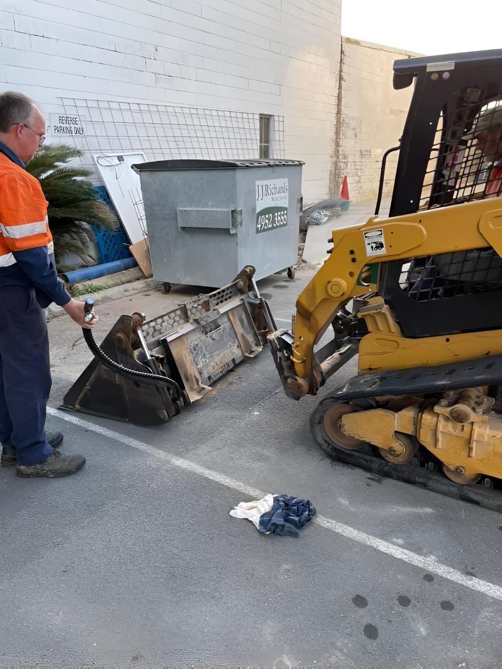 A Man Is Standing Next To A Bulldozer In A Parking Lot — Mackay Hose Fitting Services In West Mackay, QLD