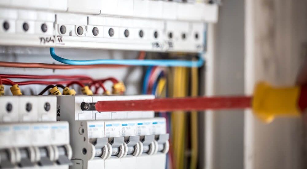 An Electrician is Working on an Electrical Box With a Screwdriver — Nick Blackman Electrical Pty Ltd In Armidale, NSW