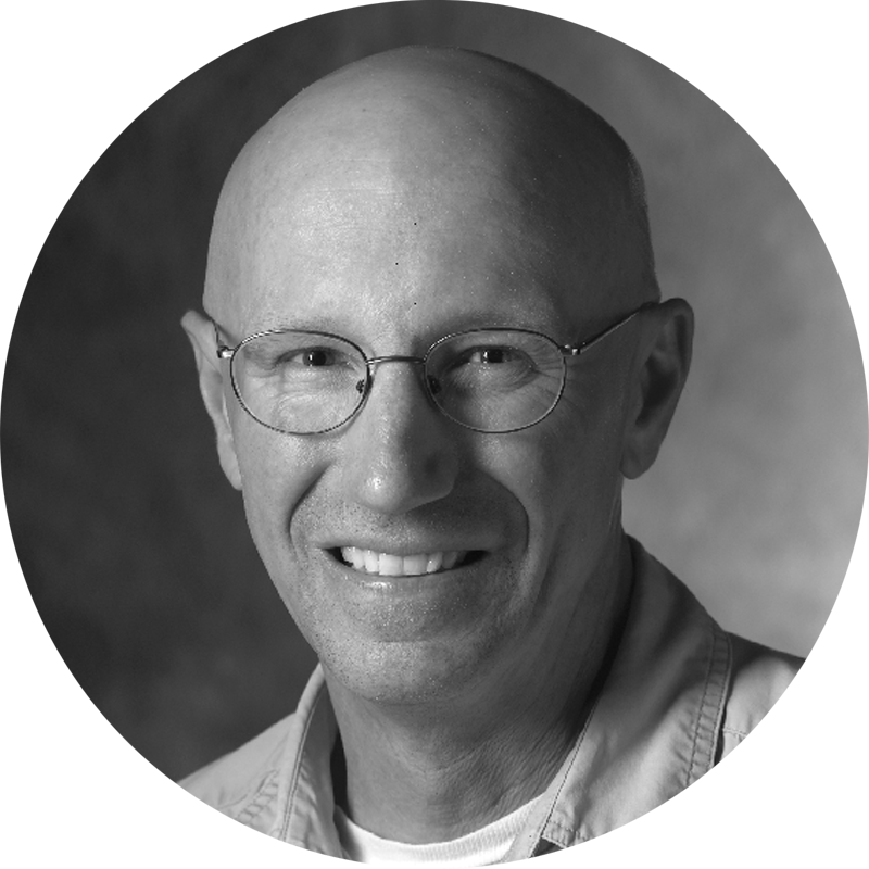 a bald man wearing glasses is smiling in a black and white photo