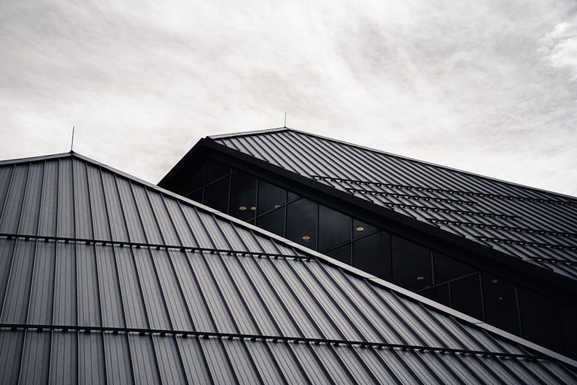 Two angled, gray metal roofs against a cloudy sky.