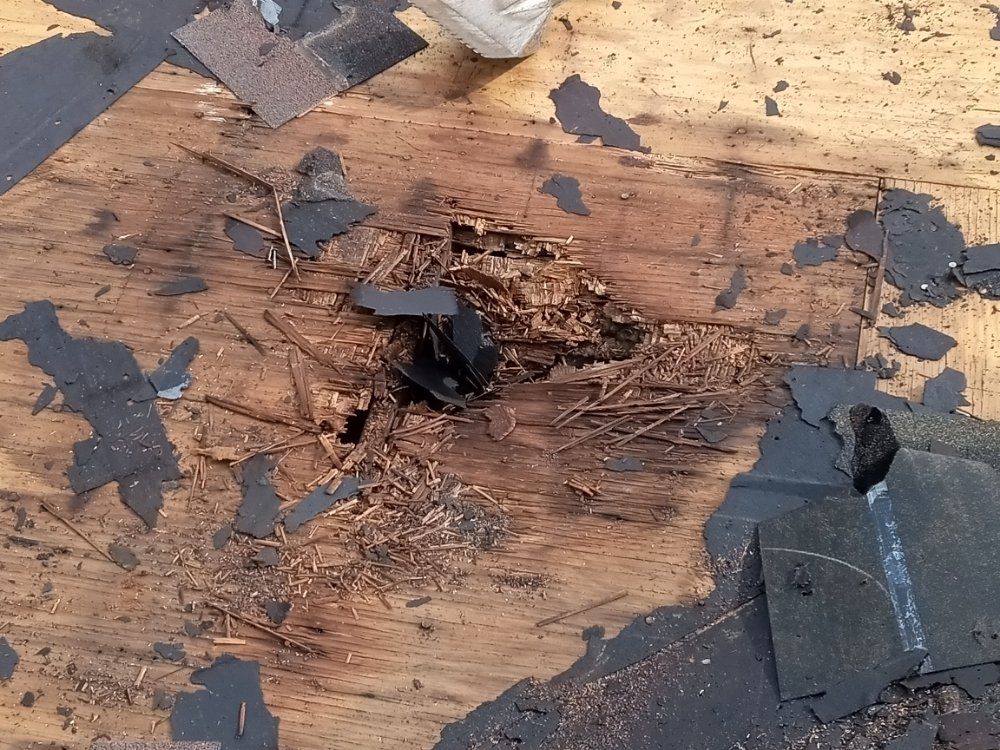 Damaged wooden roof with missing shingles and debris, possibly from water damage.