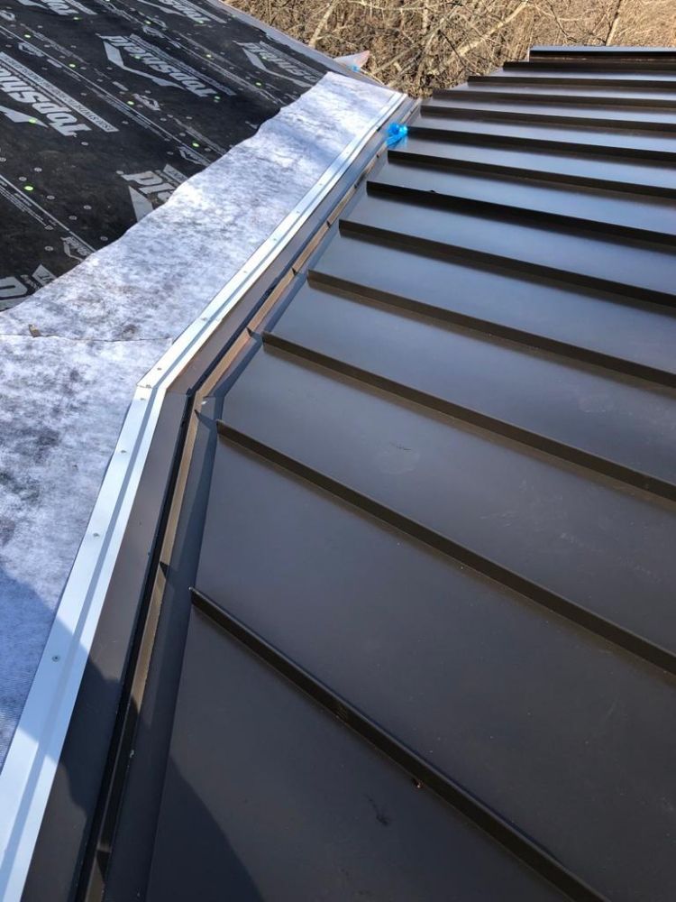 Dark metal roof with adjacent underlayment and flashing.