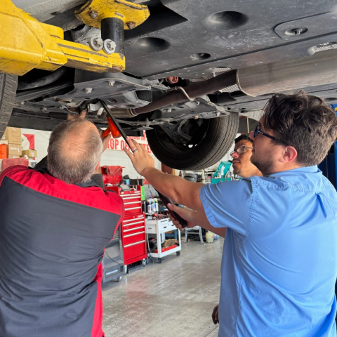 Mechanic working on a car with the hood open in a garage. | Premier Auto Service Center