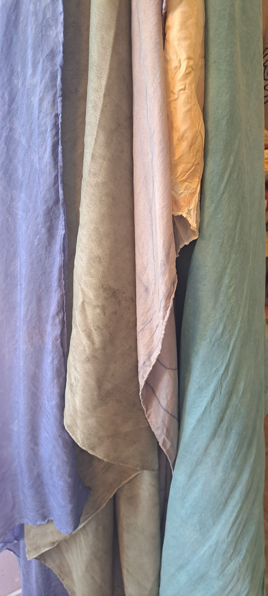 Close-up of several rolls of colorful fabric draped, including blue, green, and tan.
