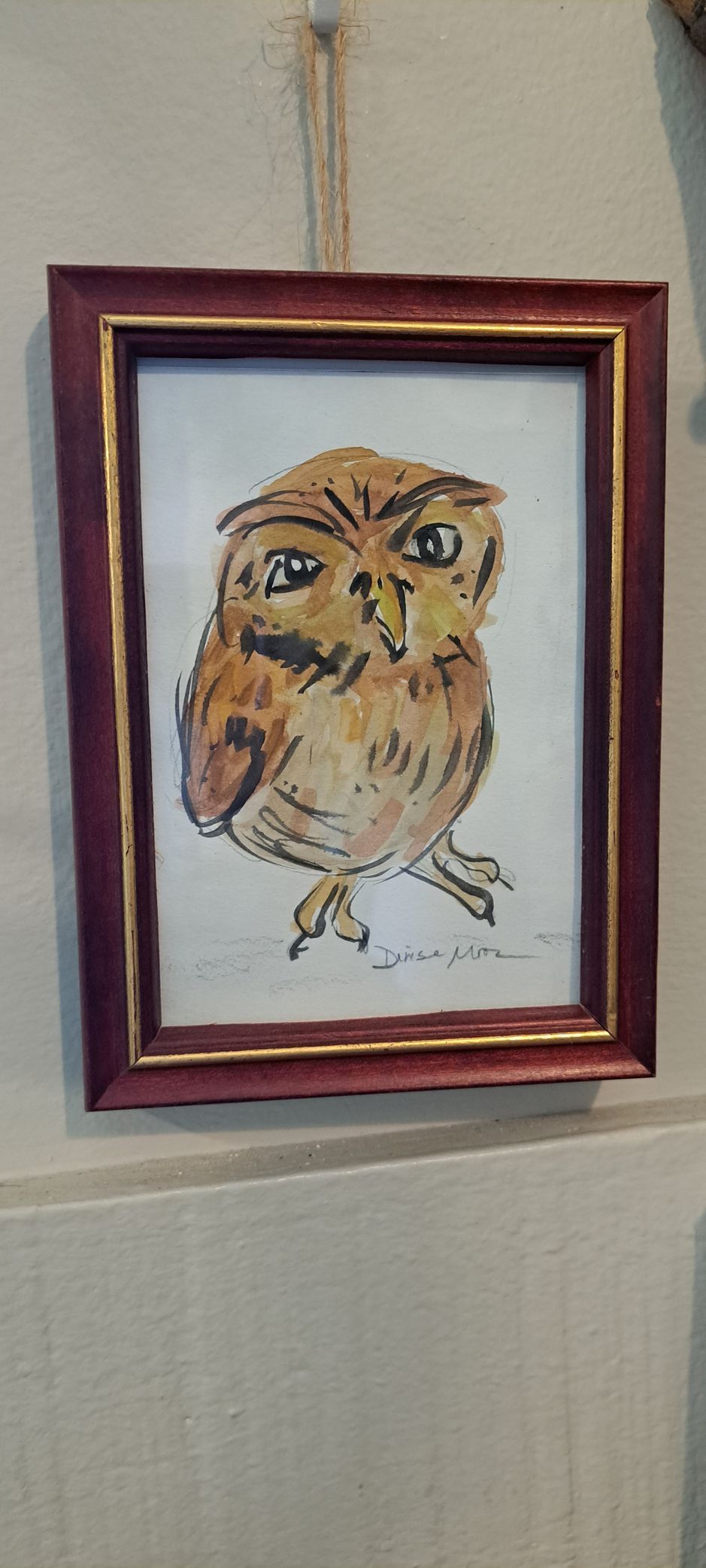 Framed painting of a brown owl with big eyes hanging on a wall.