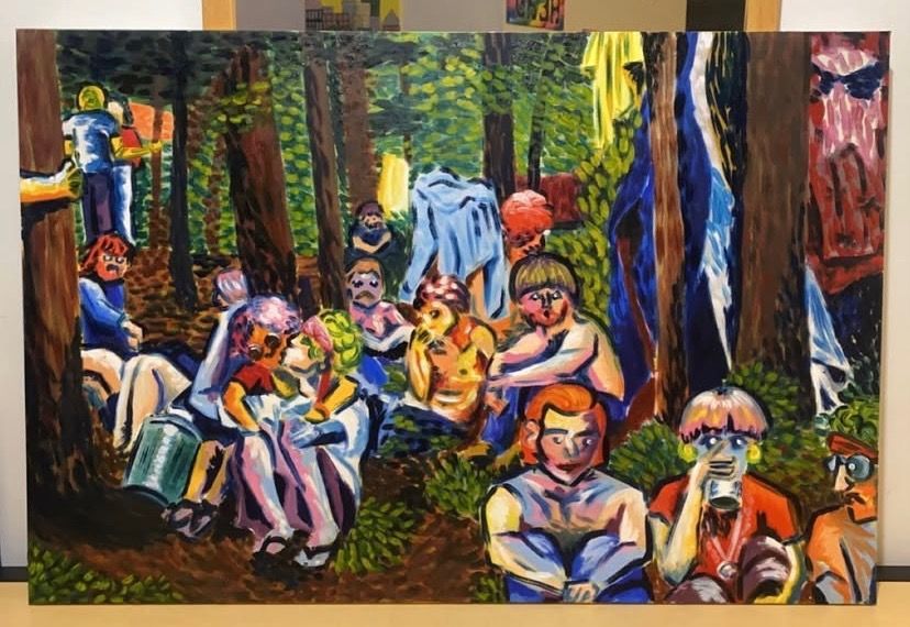 People in a forest setting, wearing colorful clothes, sitting, and standing near trees.