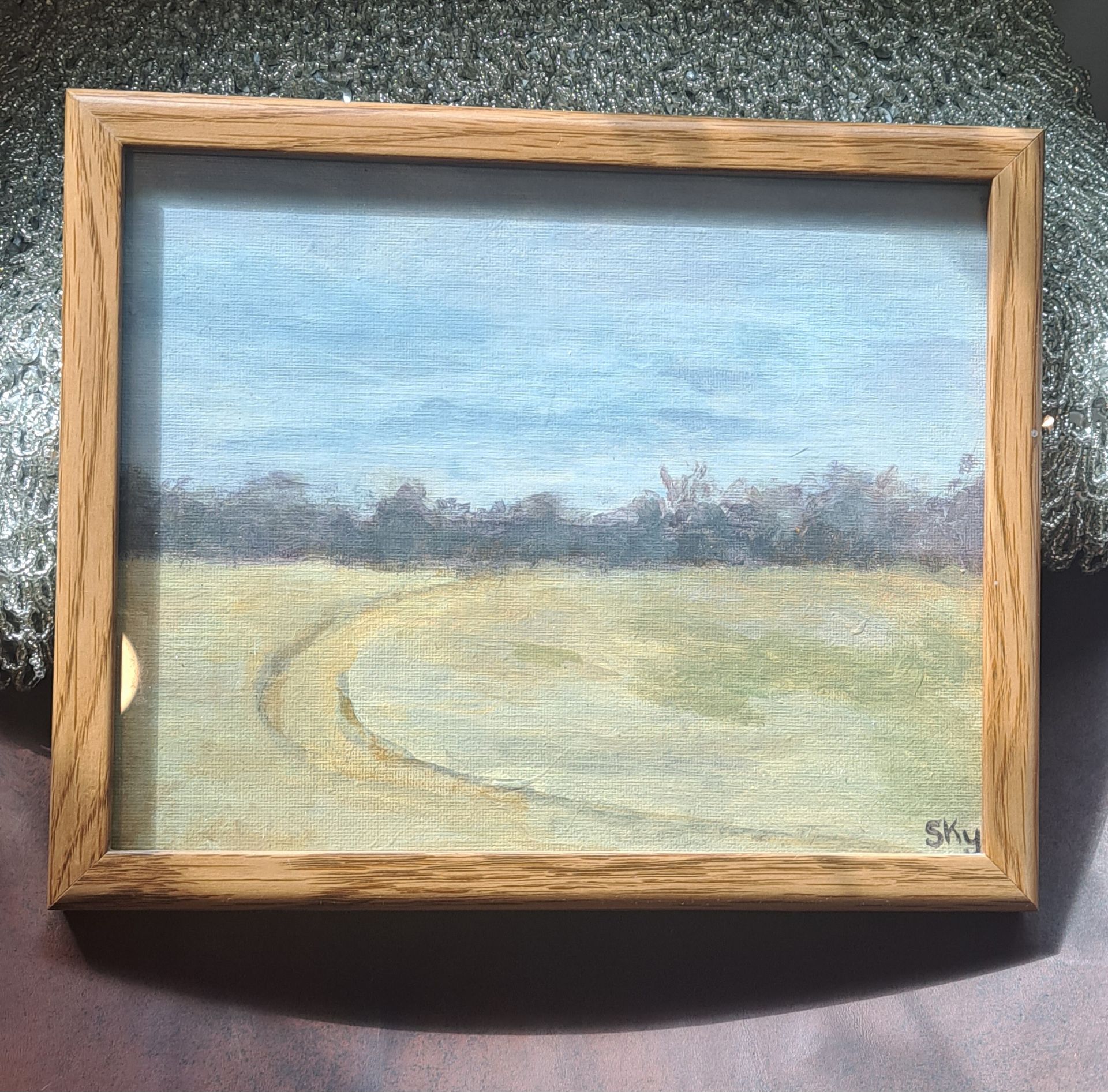 Oil painting of a landscape with a dirt path in a light wood frame.