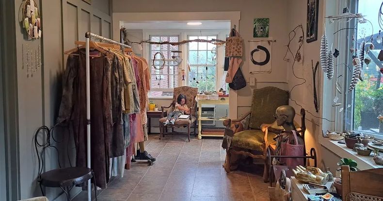 A room with a lot of clothes hanging on racks and a chair.