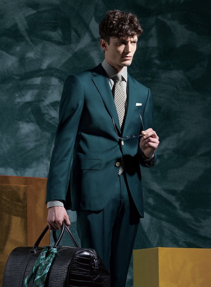 A man in a green suit is holding a black bag