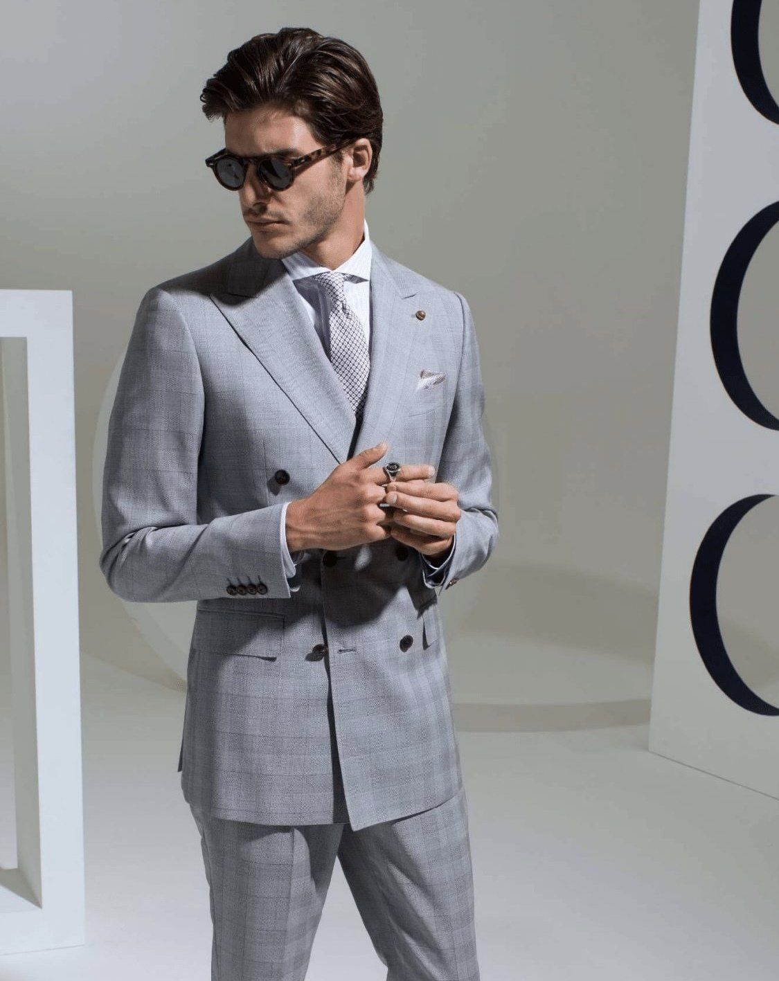 A man is wearing a grey suit and sunglasses