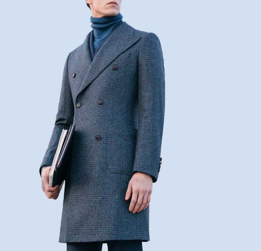 A man in a grey coat is holding a laptop