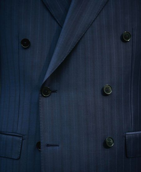 A close up of a blue suit jacket with black buttons.