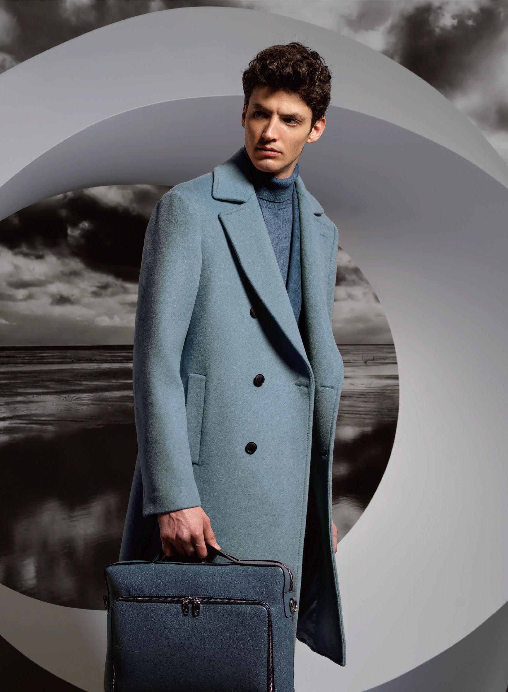 A man in a blue coat is holding a briefcase.