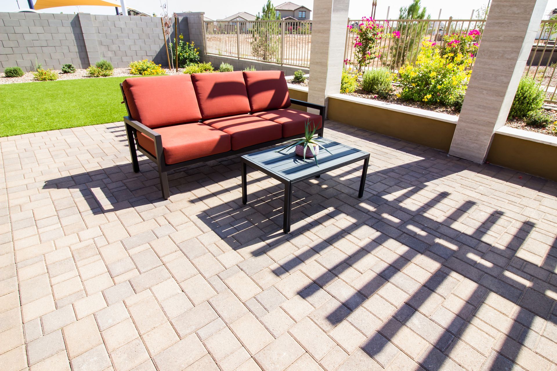 Outdoor patio with red sofa, coffee table, and brick pavers.