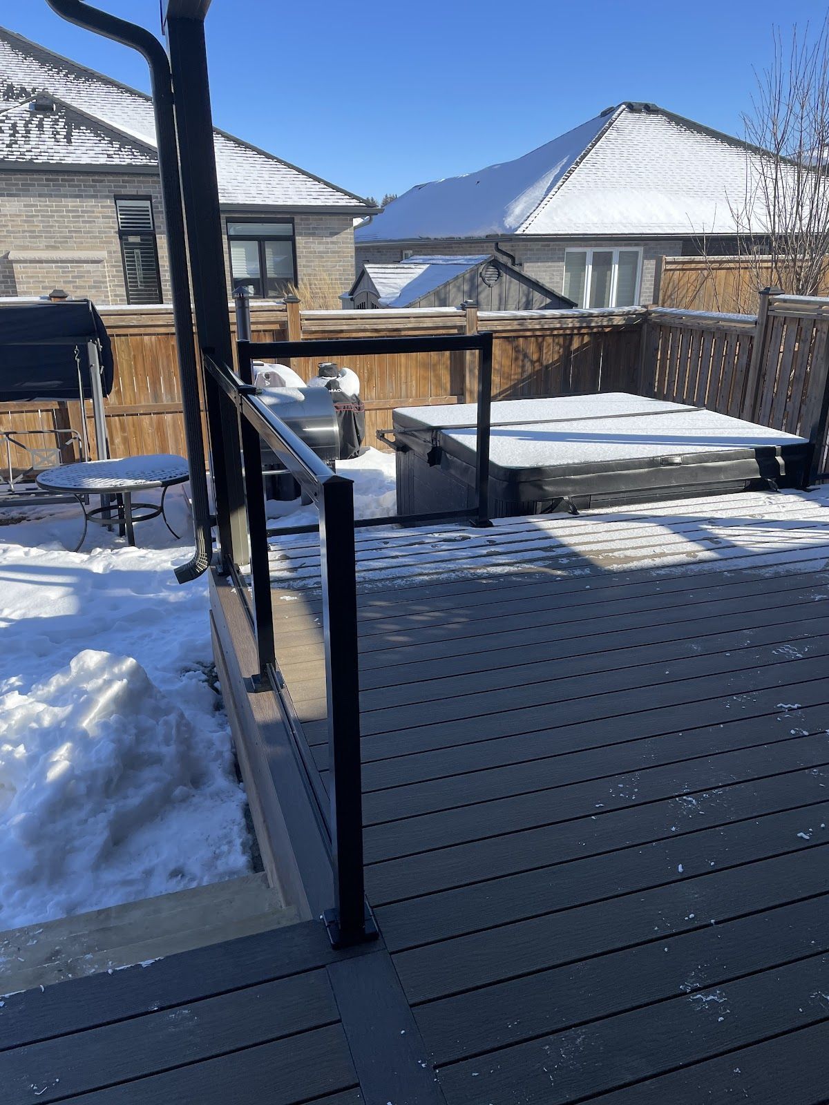 A deck with snow on it and a fence in the background