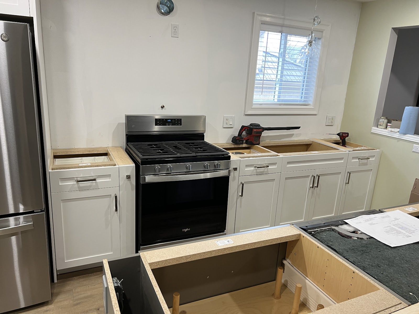 A kitchen with stainless steel appliances and white cabinets is being remodeled.