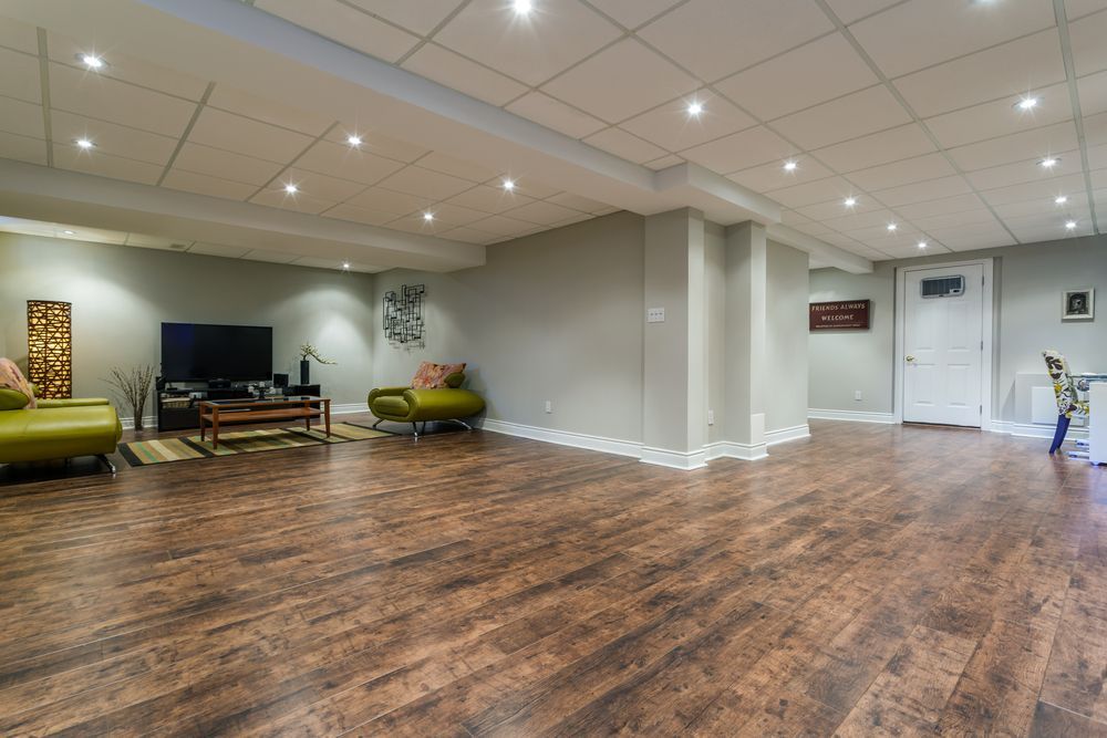 A living room in a basement with hardwood floors and a flat screen tv.