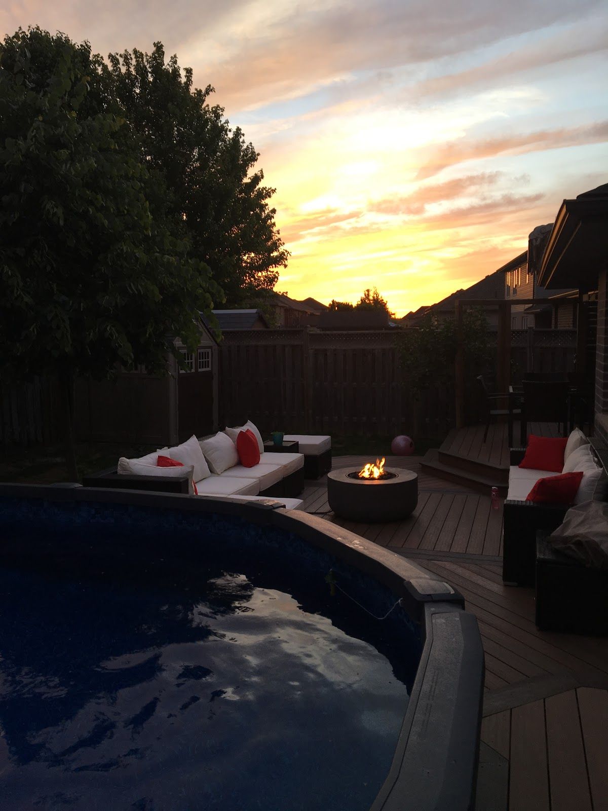 A backyard with a pool and a fire pit at sunset