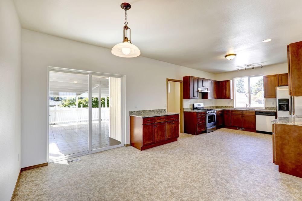 An empty kitchen with wooden cabinets and a sliding glass door leading to a patio.
