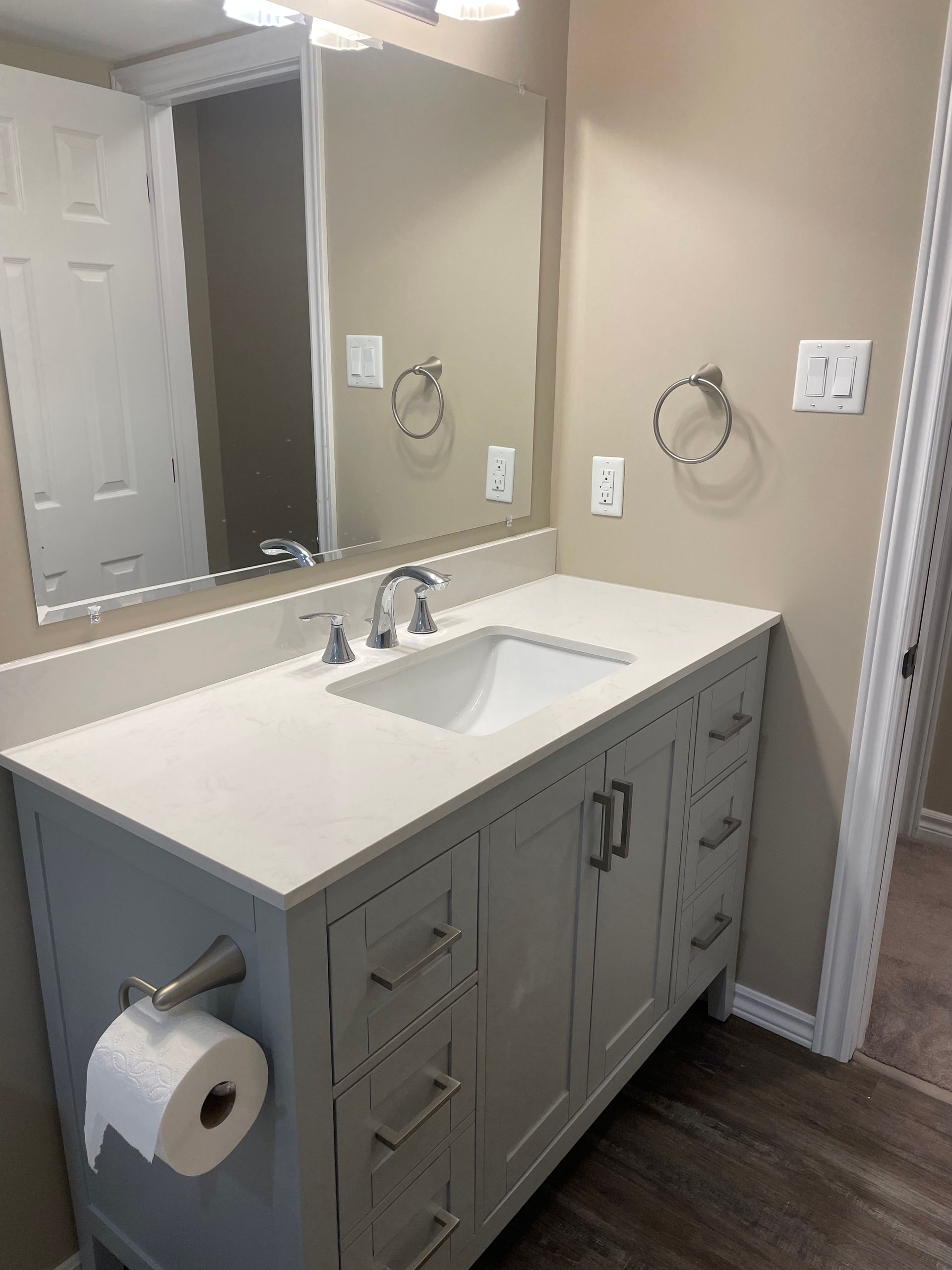 Bathroom with a white countertop, gray cabinets, mirror, and chrome fixtures.