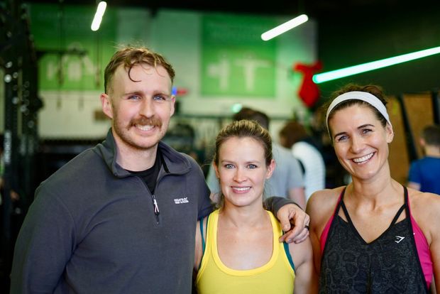 A man and two women are posing for a picture in a gym.