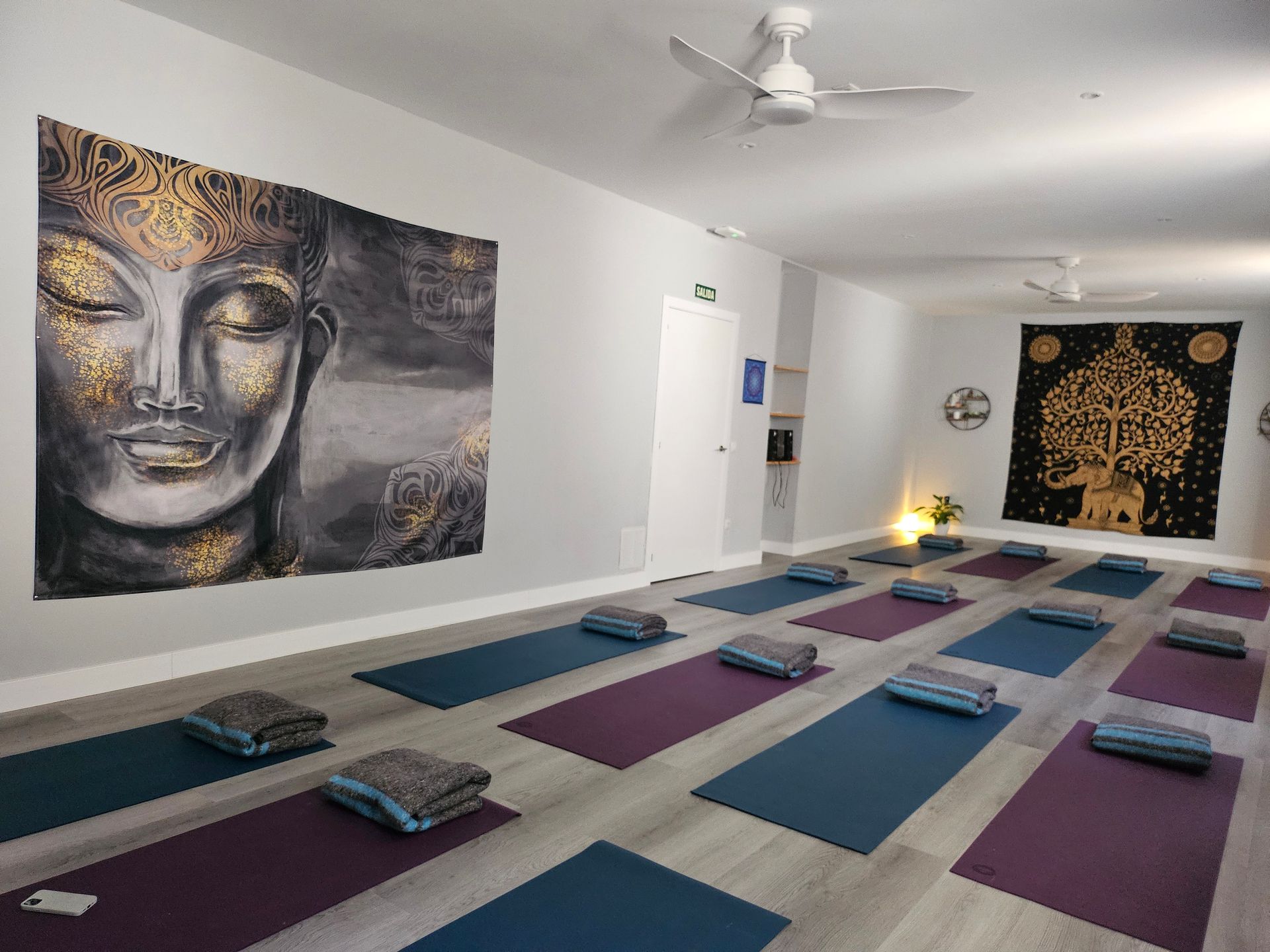 Una sala en alquiler llena de colchonetas de yoga y almohadas en el suelo.