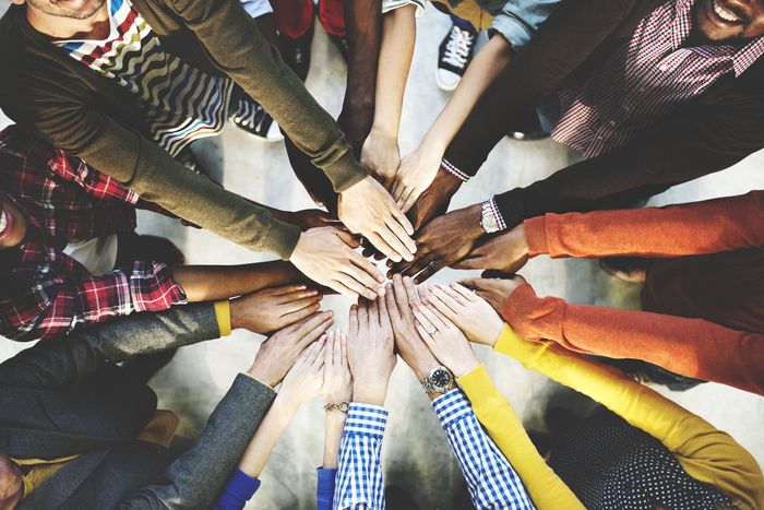 Hands of diverse people joined together in a circle, symbolizing unity and teamwork.