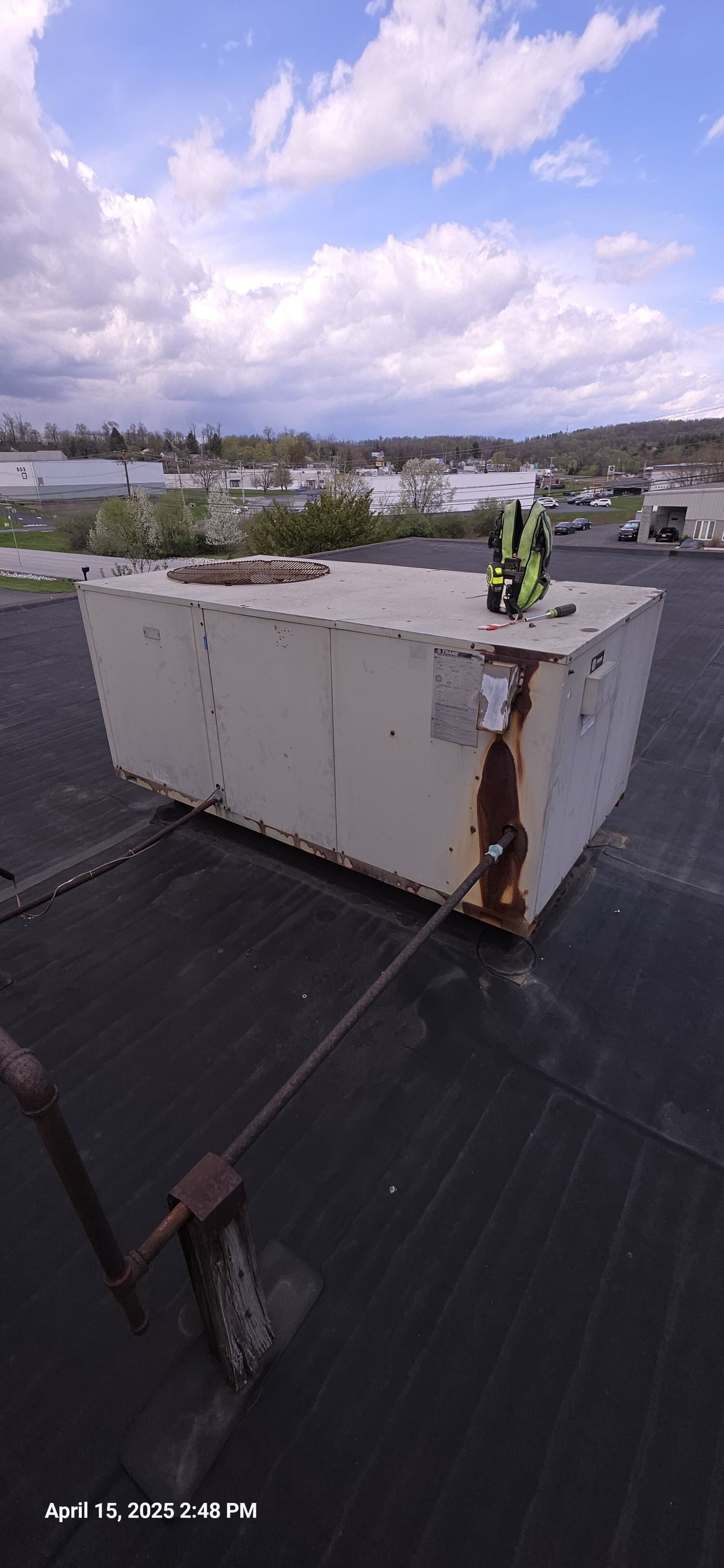 White box on a rooftop, secured by a cable. Cloudy sky.