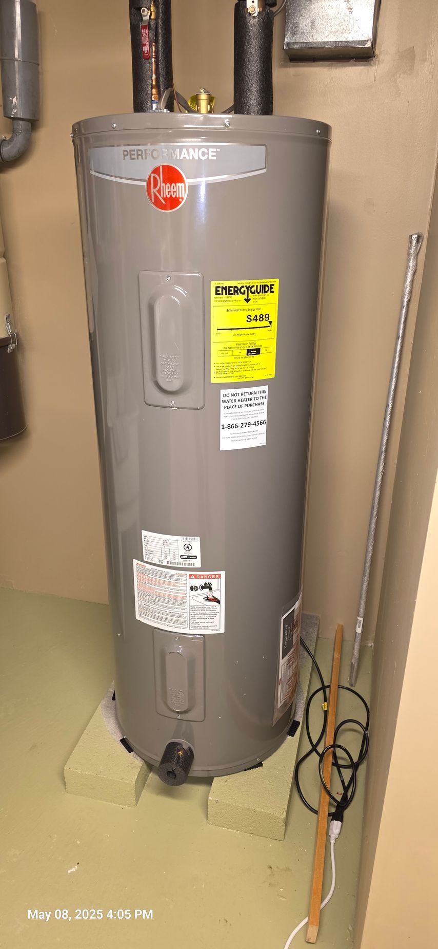A Rheem water heater in a utility room. It is standing on two blocks. A yellow energy label is visible.