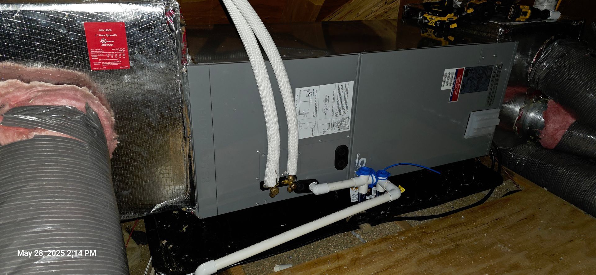 HVAC unit with white pipes and black base, in a wooden structure.