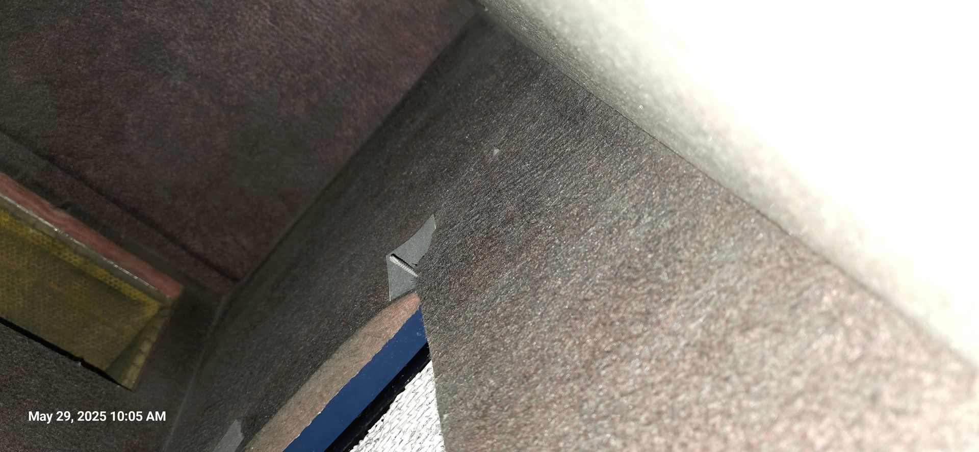 Interior corner with textured walls and ceiling, a glimpse of a window with a blue frame.