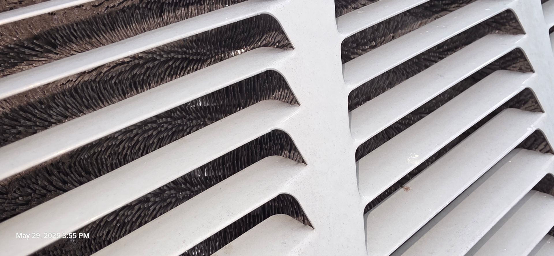 Close-up of a white vent with slatted design, offering glimpses of a dark, textured interior.