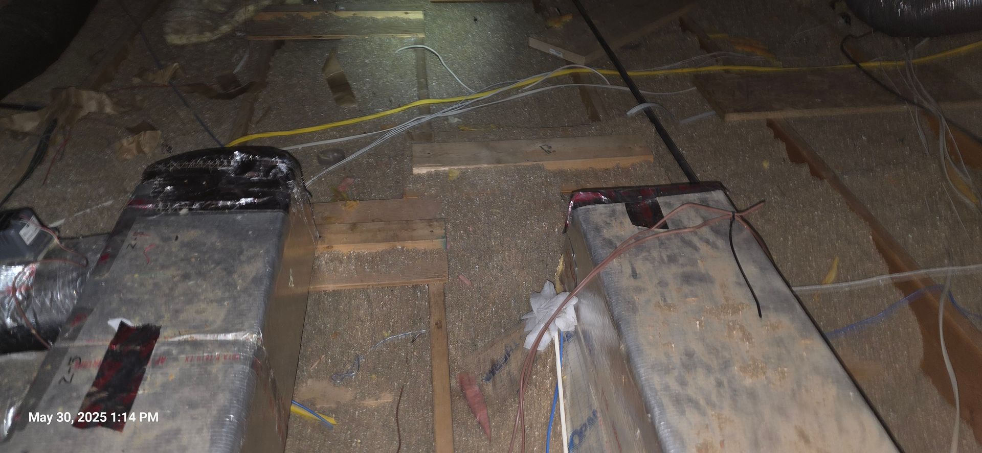 An attic with exposed rafters, ductwork, and electrical wiring.