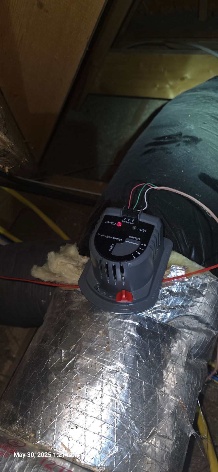Gray HVAC control unit installed on ductwork in a crawl space.