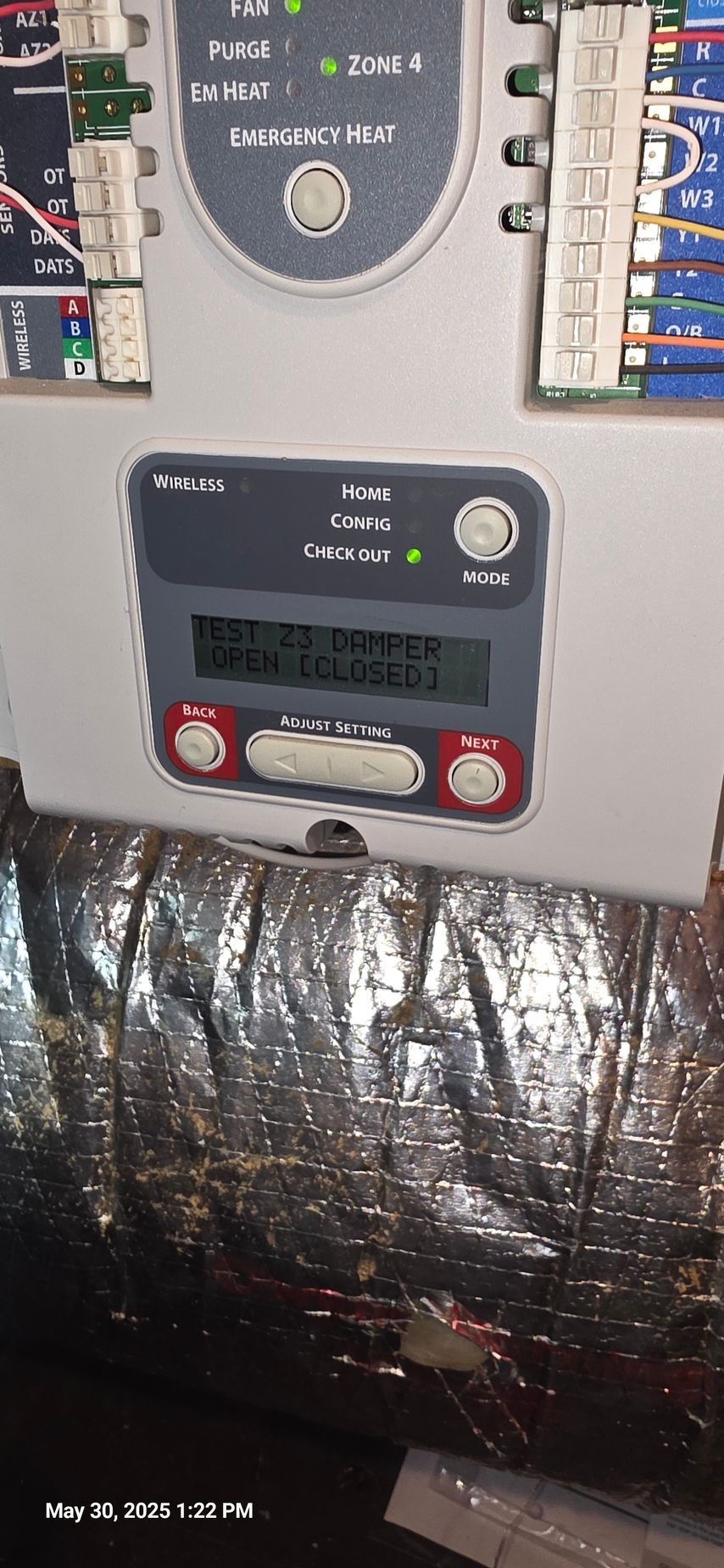 A control panel showing text, lights, and buttons. It's set in ductwork with silver insulation.