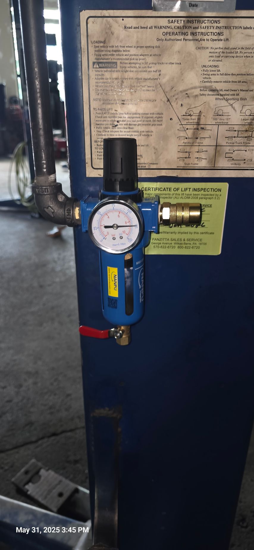 Blue air filter with pressure gauge, red drain valve, and black regulator on a blue machine.