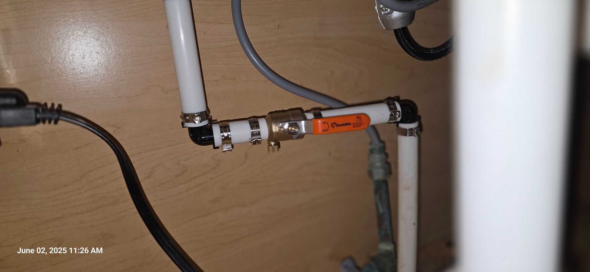 White pipes and a brass valve are connected with clamps.