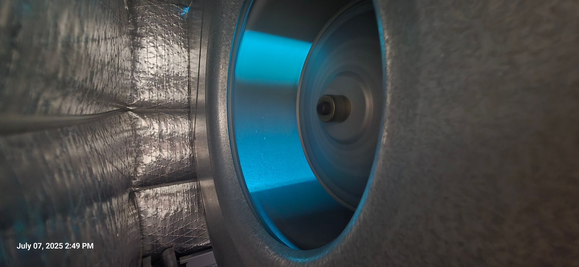 Inside view of an industrial fan with a spinning blue blade, metal casing.